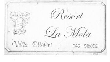 Hotelname-Plaque mit 'Resort La Mola' und 'Villa Ottolini' sowie der Telefonnummer '045-516008'.