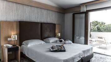 A modern hotel room with a large bed, a bedside table with a phone and lamp, and a tray with breakfast items.