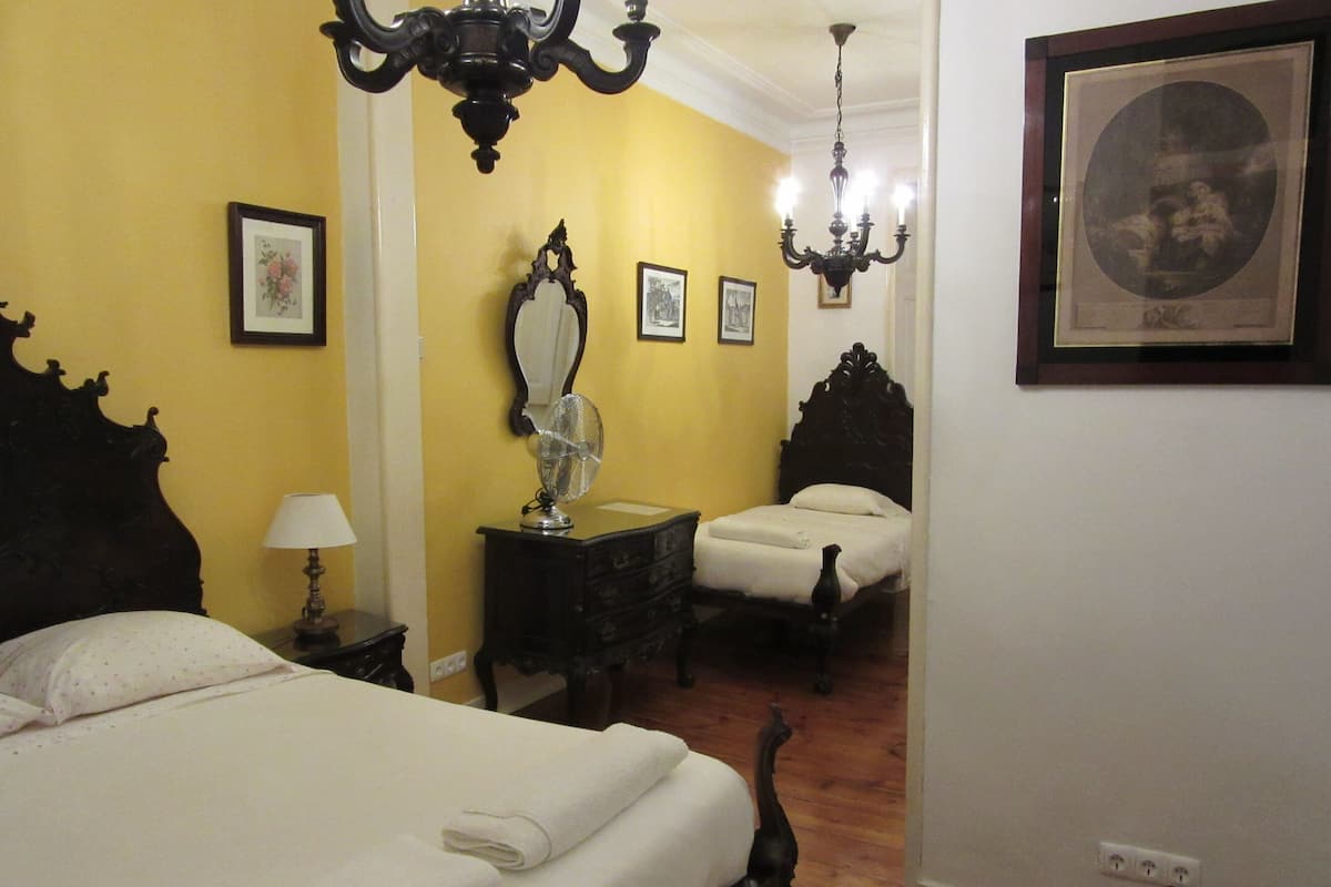 Une chambre à coucher avec un lit, une commode, un ventilateur et un lustre.