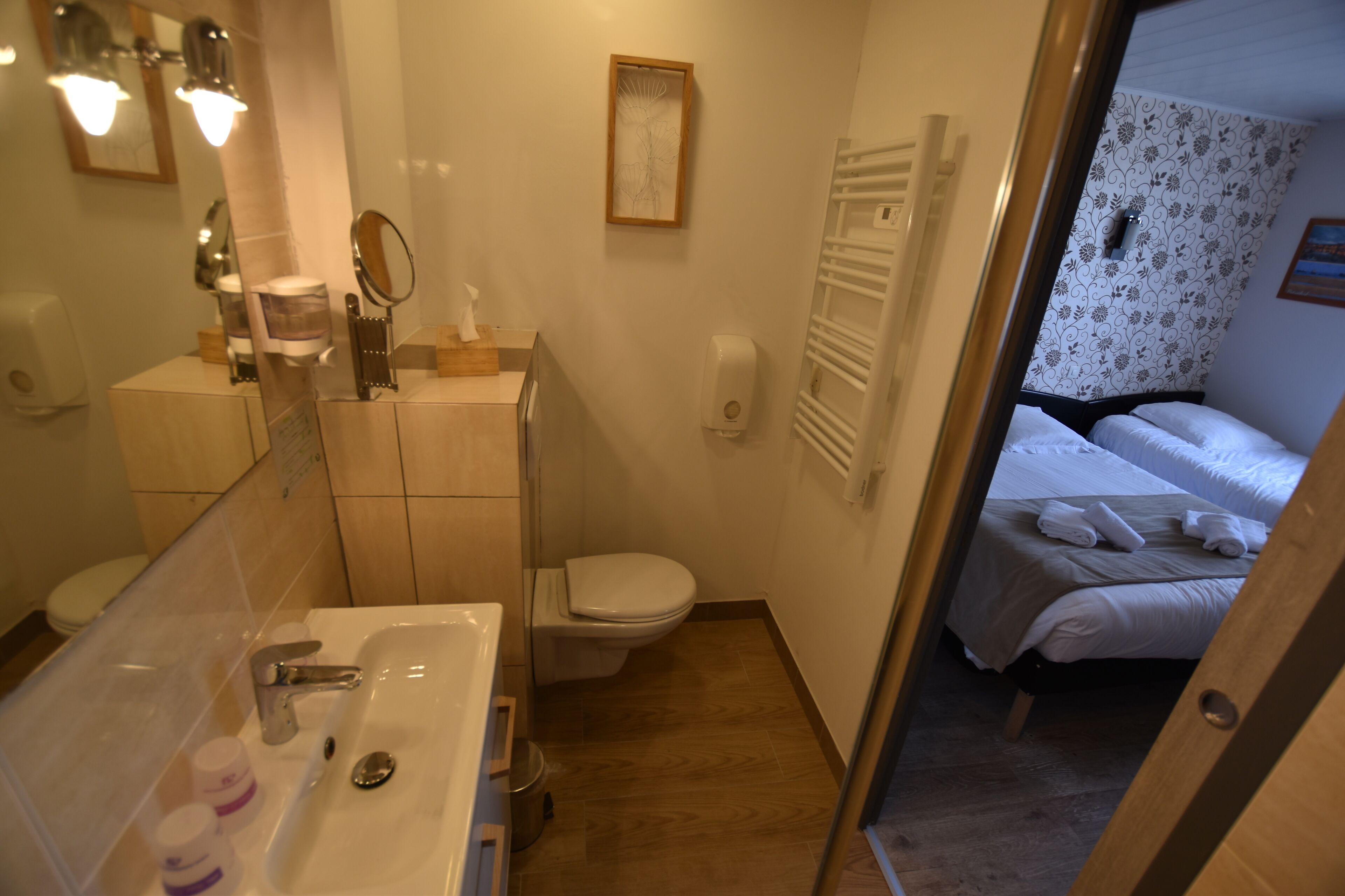 Un baño con lavabo, espejo, inodoro y mesita de noche con una toalla.
