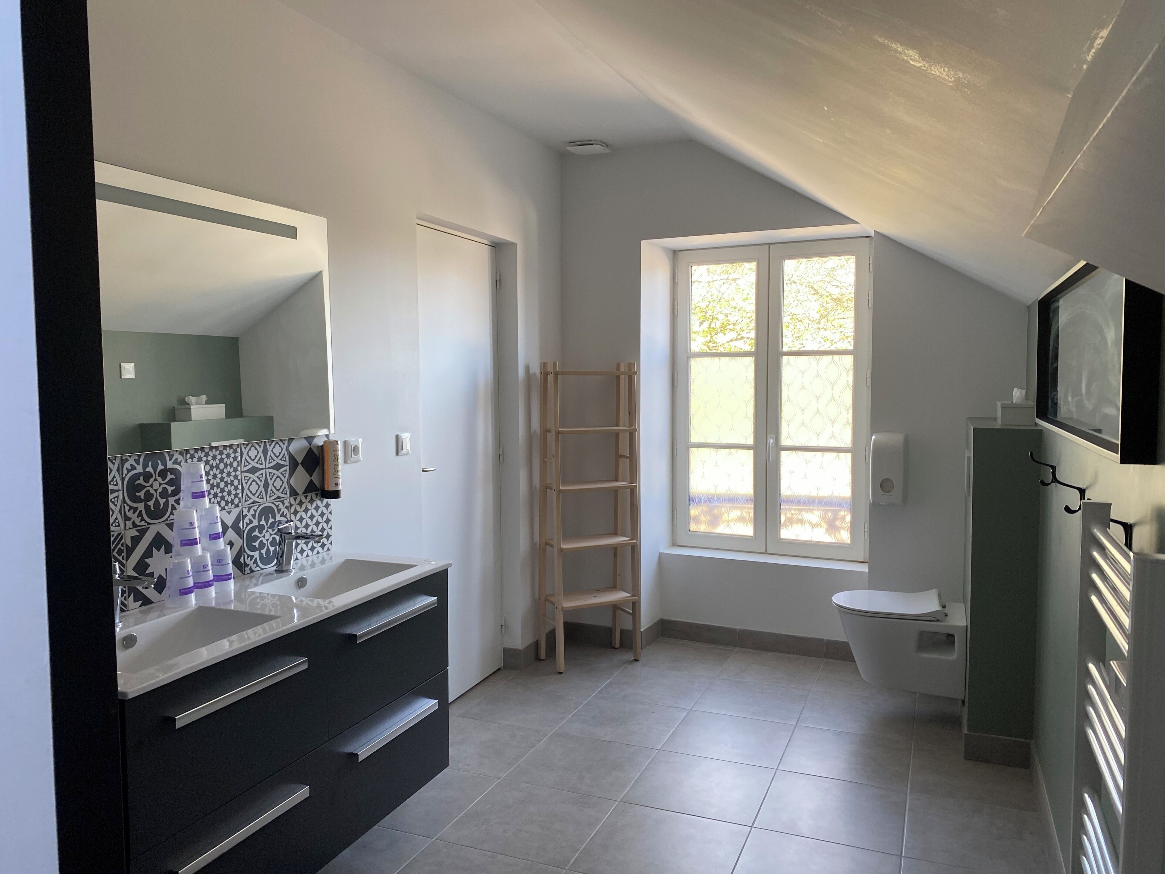 Een moderne badkamer met een grote spiegel, een wastafel, een toilet en een raam.