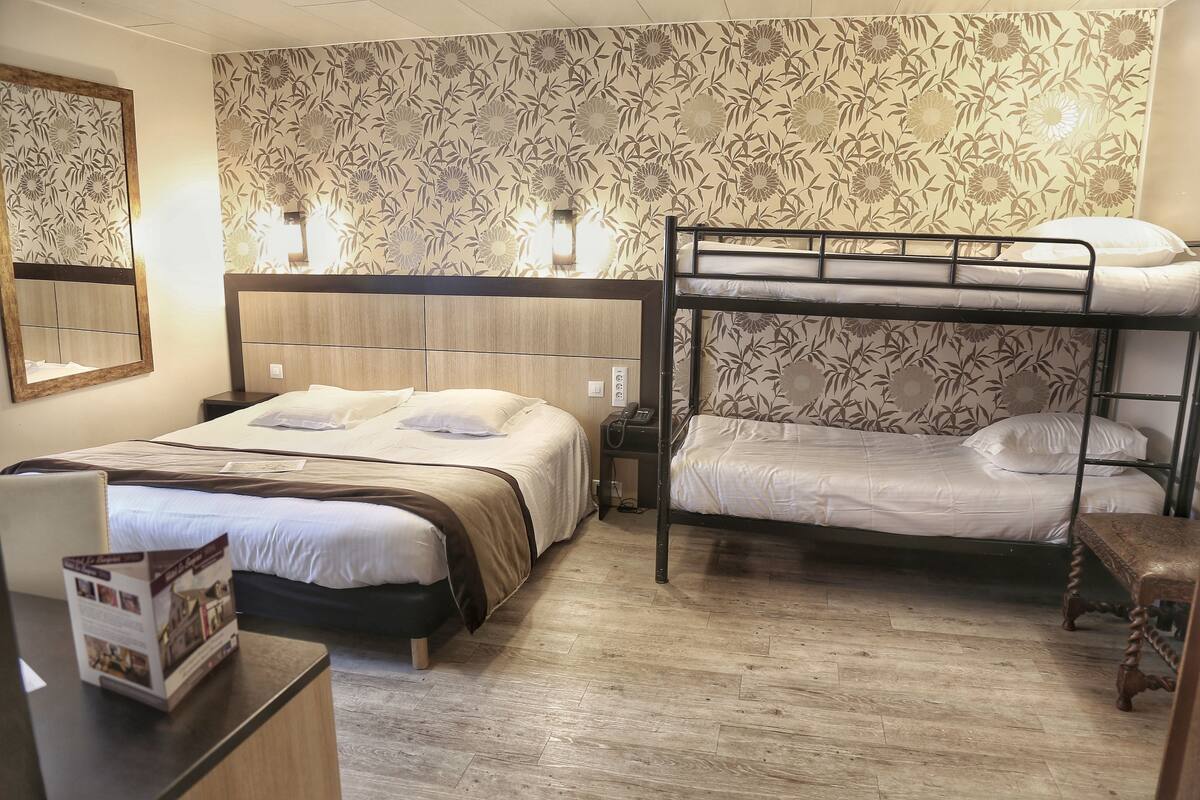 A room with two beds, a desk, and a mirror.
