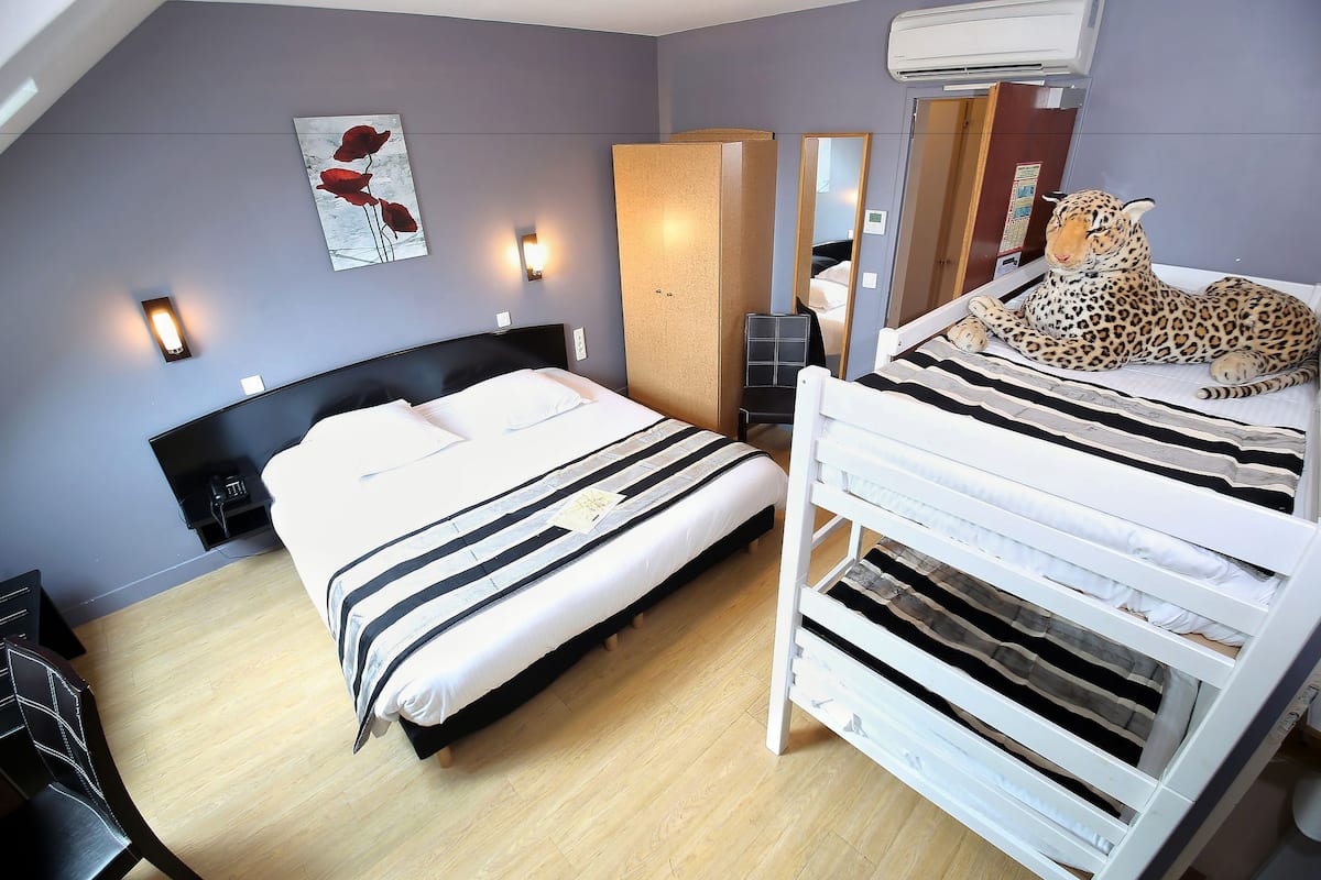 Une chambre d’hôtel avec un lit, un miroir, un léopard et un tableau accroché au mur.