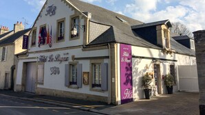 A building with a sign reading "Hotel Le Bayeux" and a purple banner with "Hotel Le Bayeux" written on it. - Hotel Le Bayeux (Bayeux)