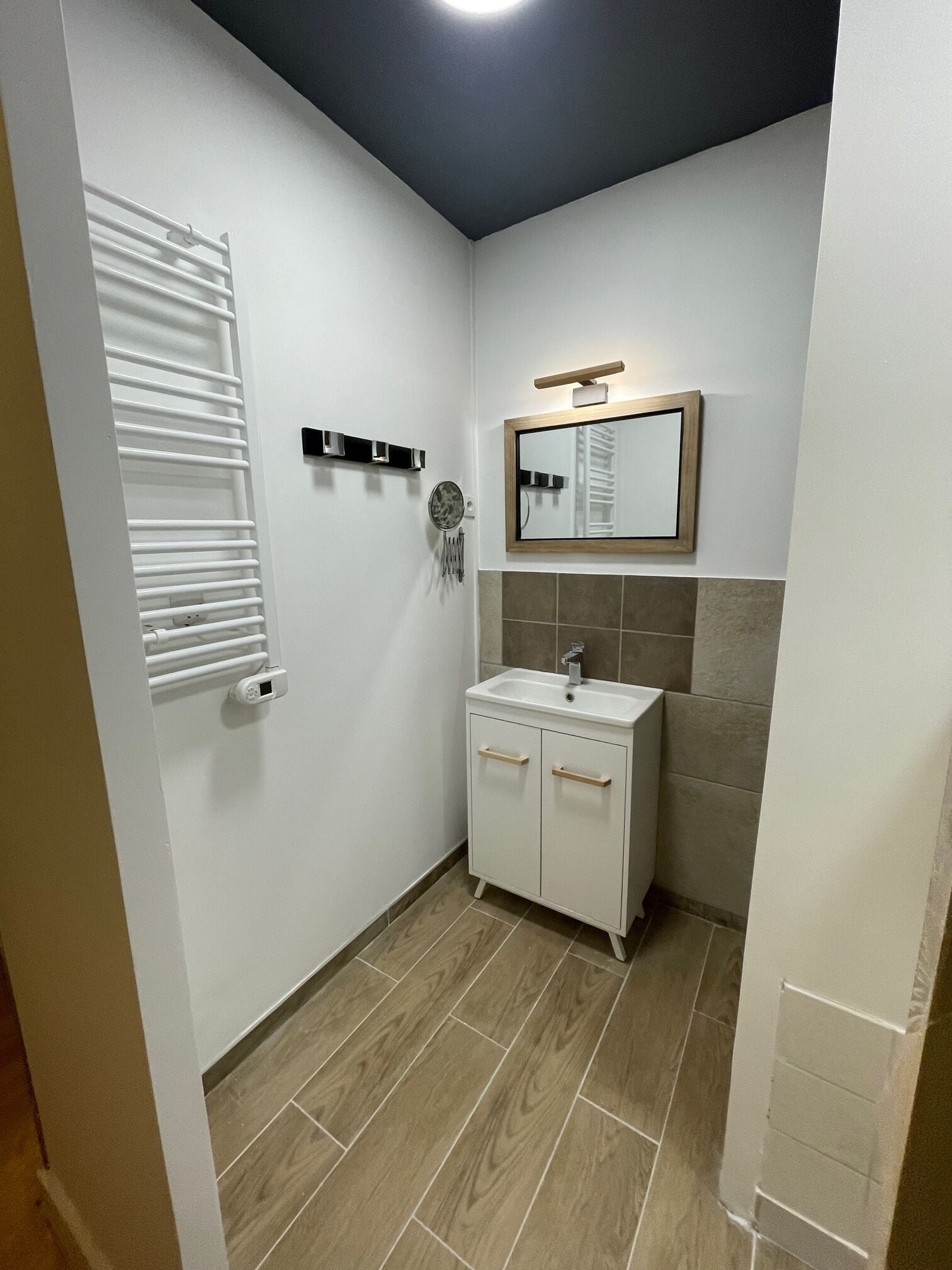 A bathroom with a white sink, a mirror, and a towel rack.