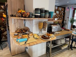 A buffet setup with various food items and serving utensils. - Hotel Le Bayeux (Bayeux)