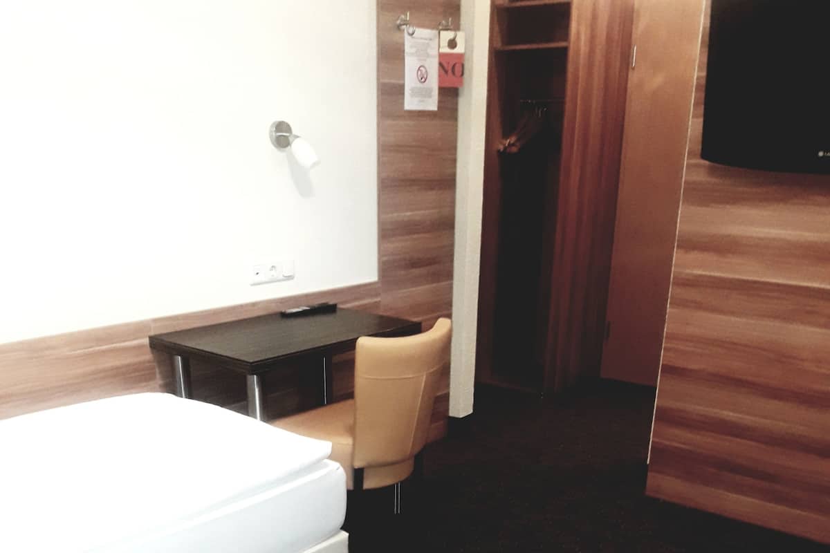 Une chambre d’hôtel équipée d’un lit, d’un bureau, d’une chaise, d’une armoire et d’un téléviseur.
