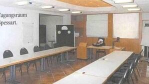 A classroom with long tables, a whiteboard, and a projector screen.