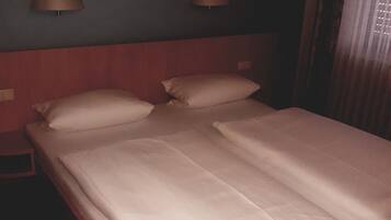 Ein Hotelzimmer mit einem Doppelbett, zwei Nachttischlampen und einem gerahmten Kunstwerk an der Wand.