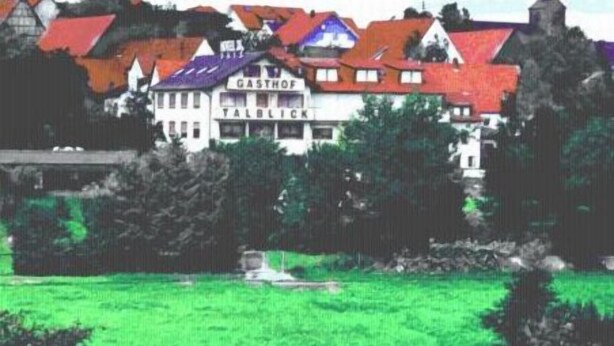 A building with a sign reading "GASTHOF TALBLICK" surrounded by trees and a green field.