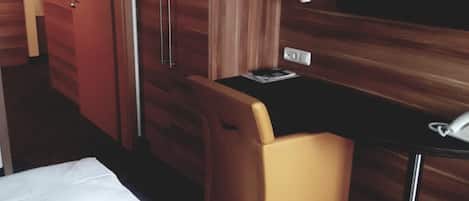 A hotel room with a bed, a desk, a chair, a wardrobe, and a television.