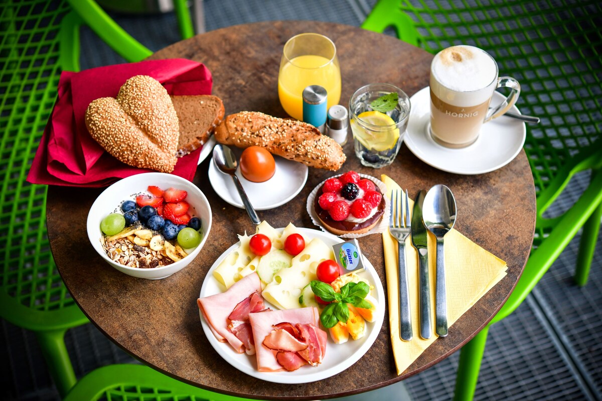 A round table with breakfast items including bread, cheese, tomatoes, and a cup of coffee.