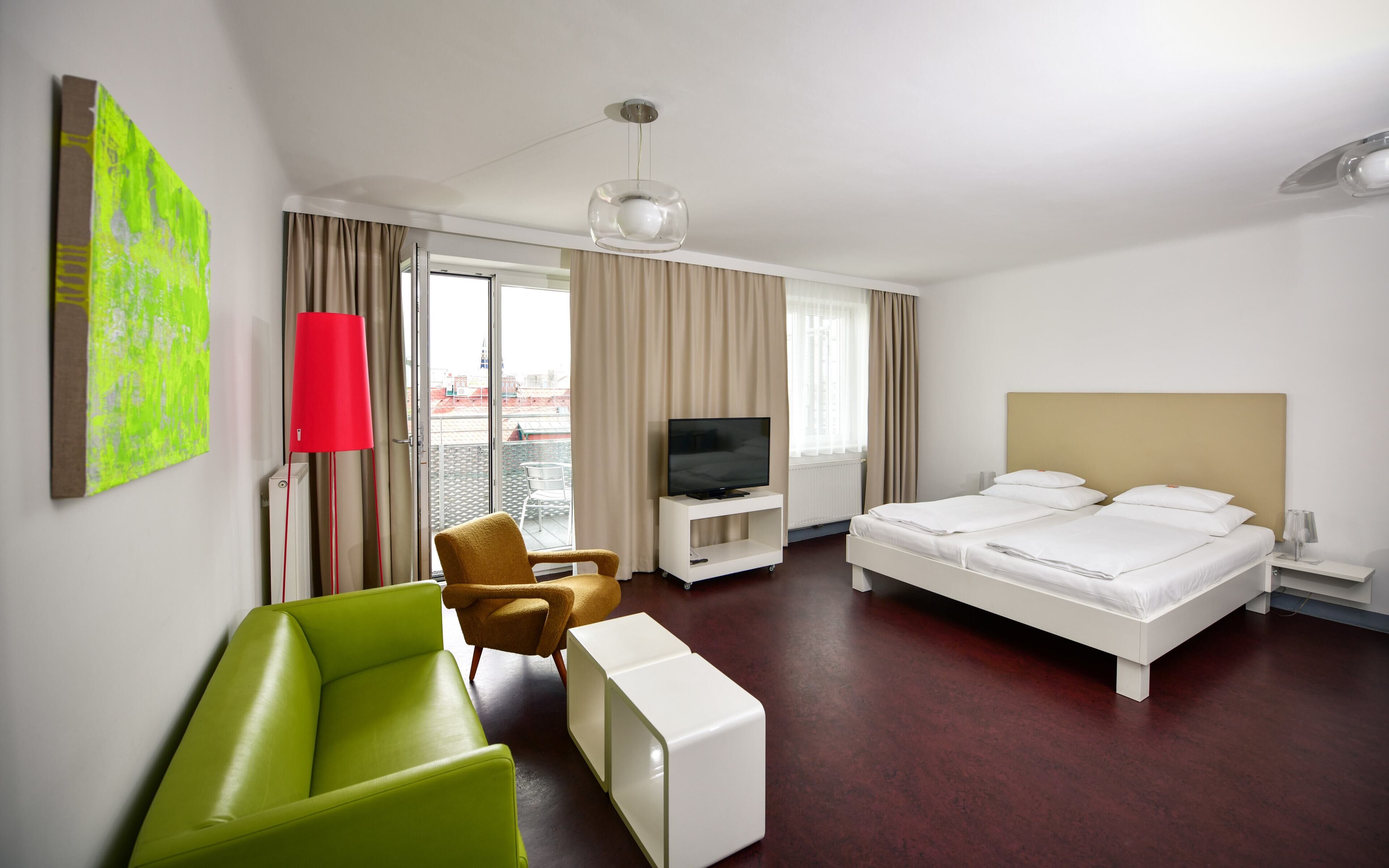 Een hotelkamer met een bed, een televisie, een bank, een stoel en een raam.