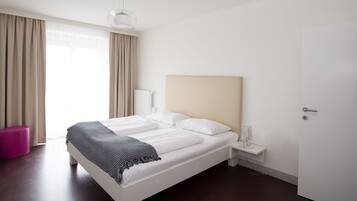 Una habitación de hotel moderna con una cama grande, una mesita de noche, una lámpara y una puerta.