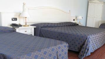 A hotel room with two beds, a bedside table with a lamp, a phone, and a wardrobe.