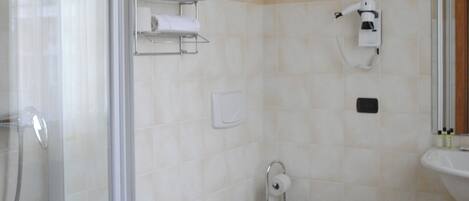A bathroom with a glass shower enclosure, a bidet, a toilet, and a sink.