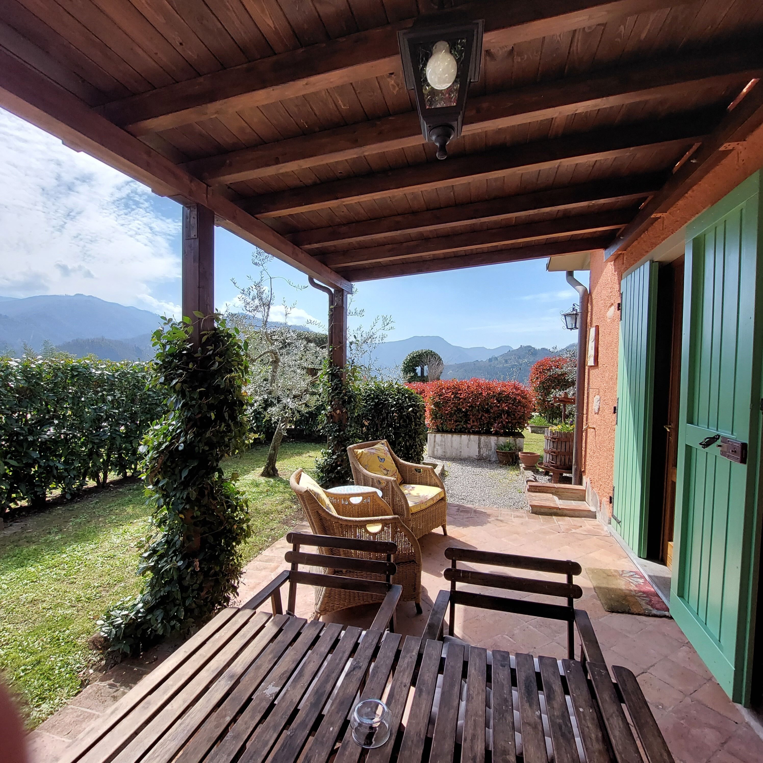 A covered patio with wicker furniture and a view of mountains.