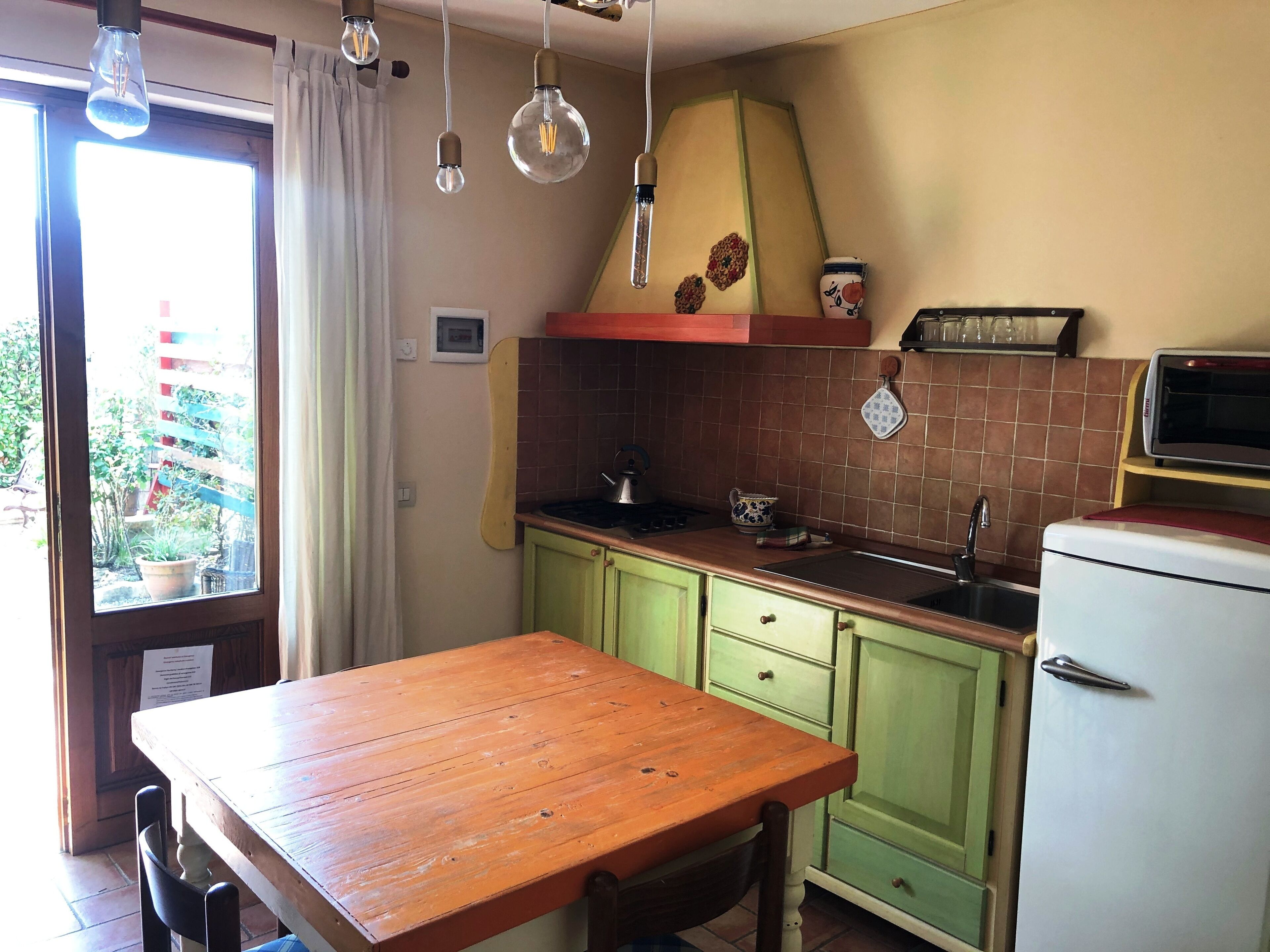 Una cocina con una mesa de madera, gabinetes verdes, una estufa y un microondas.