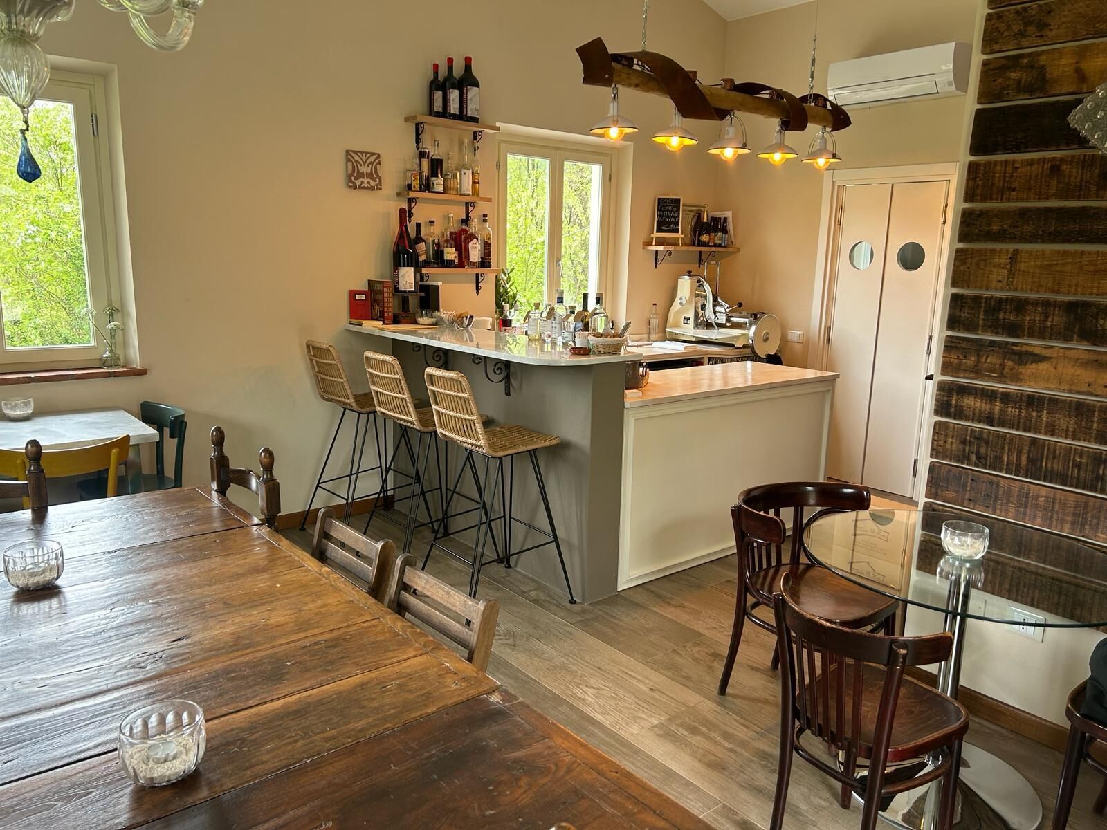 A kitchen with a bar area, wooden bar stools, and a dining table with chairs.