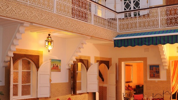 Un intérieur marocain traditionnel avec un coin repas, des canapés et un balcon.