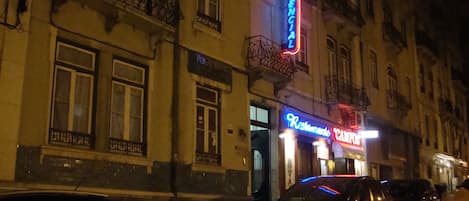A building with a 'Restaurant' sign and a 'Residence' sign, featuring balconies and a street view.