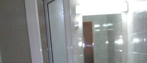 Un baño con cabina de ducha de vidrio, lavamanos y espejo.