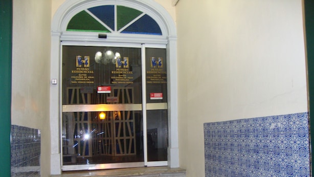 L’entrée d’un hôtel avec une porte en verre, un escalier menant à l’étage supérieur et un mur orné de motifs.