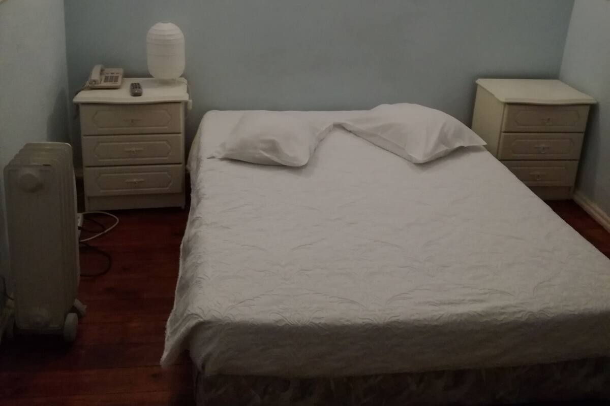 Ein Schlafzimmer mit einem Bett, zwei Nachttischen, einer Heizung und einer Wandleuchte.