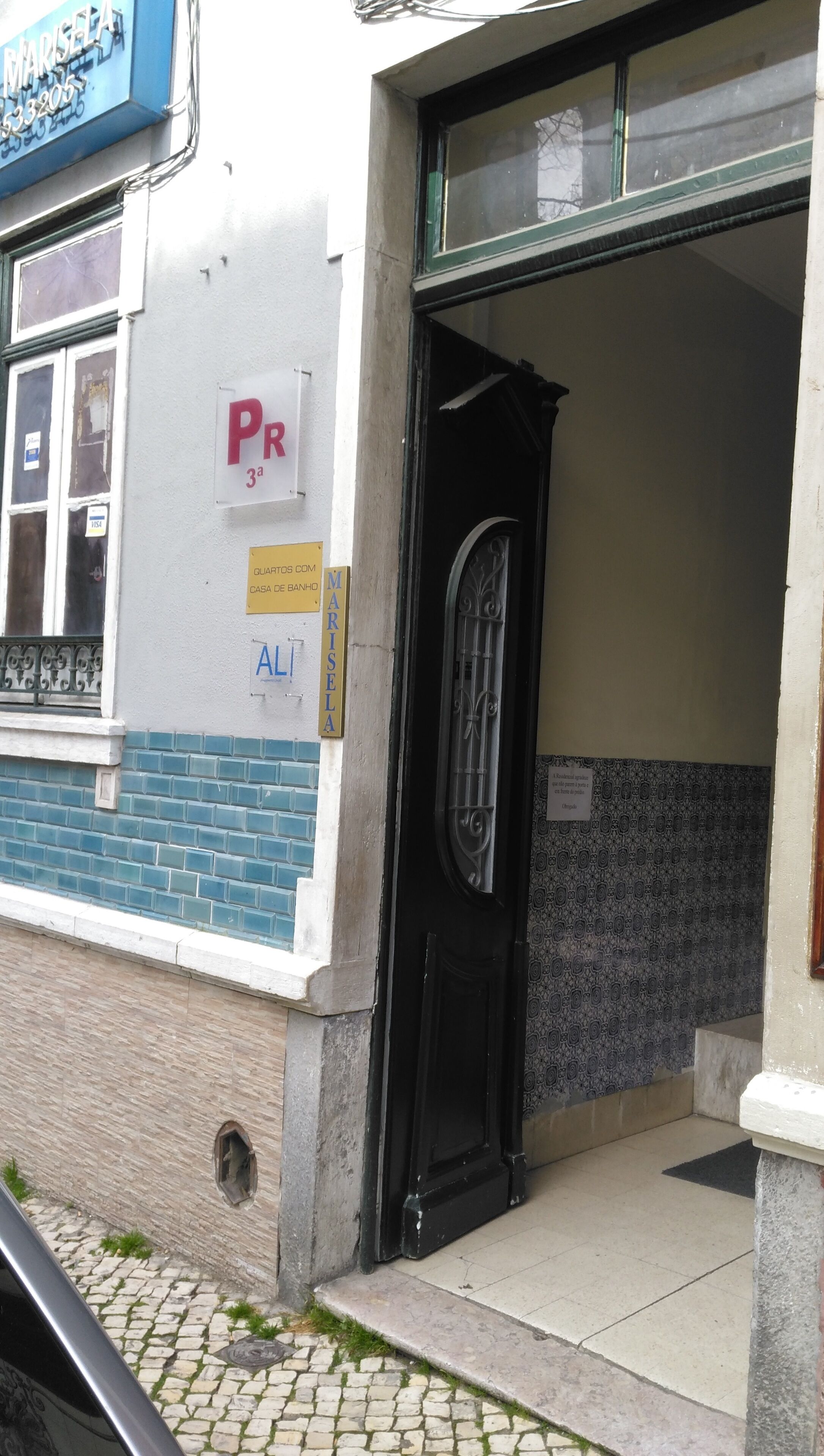 A building entrance with a black door, a visible window, and a sign indicating a parking space.