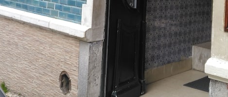A building entrance with a black door, a visible window, and a sign indicating a parking space.