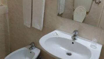 Un baño con lavamanos, bidé y toallero.