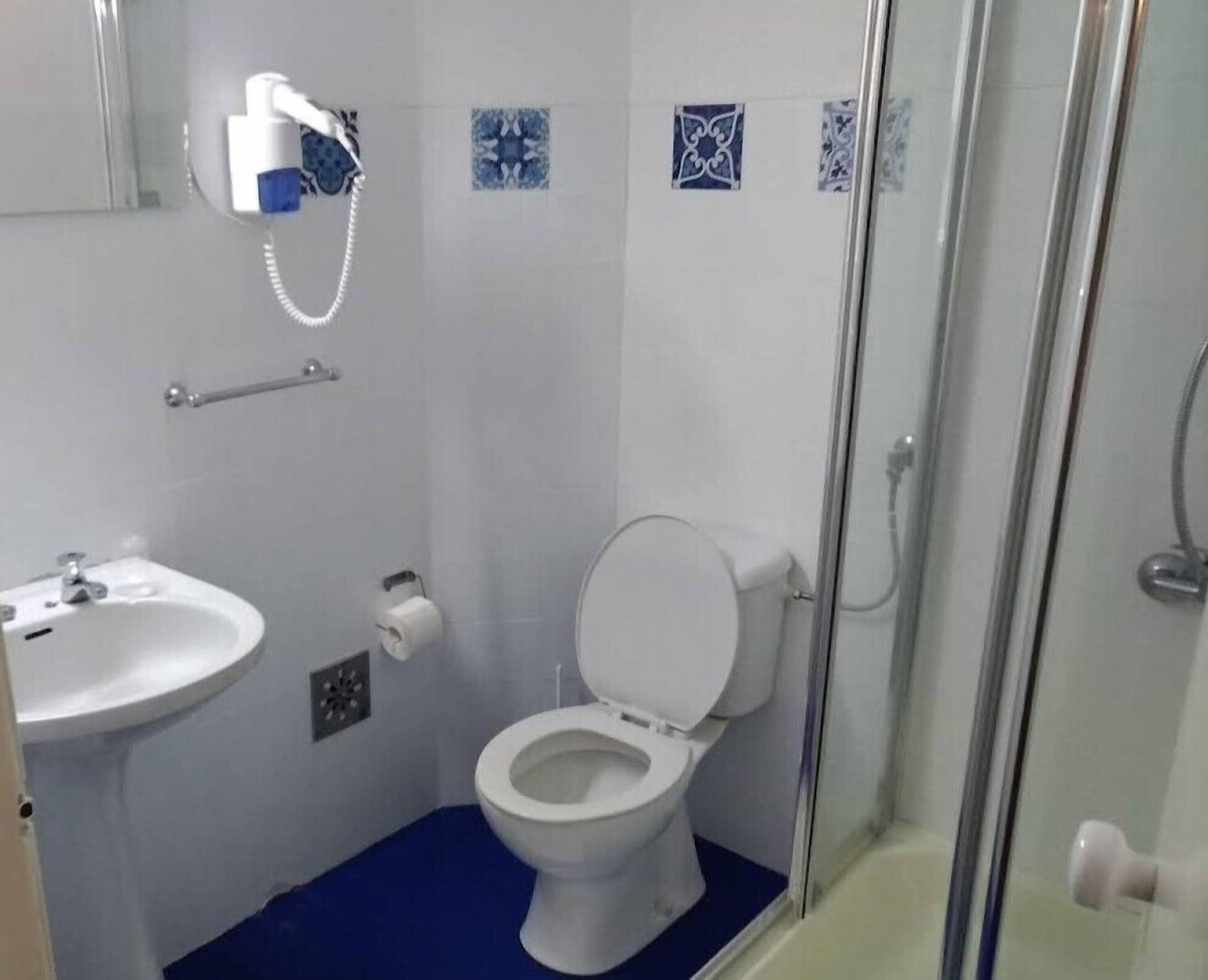 A bathroom with a white toilet, a sink, and a shower area.