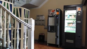 Un escalier avec une rampe, un distributeur automatique et un réfrigérateur rempli de boissons.