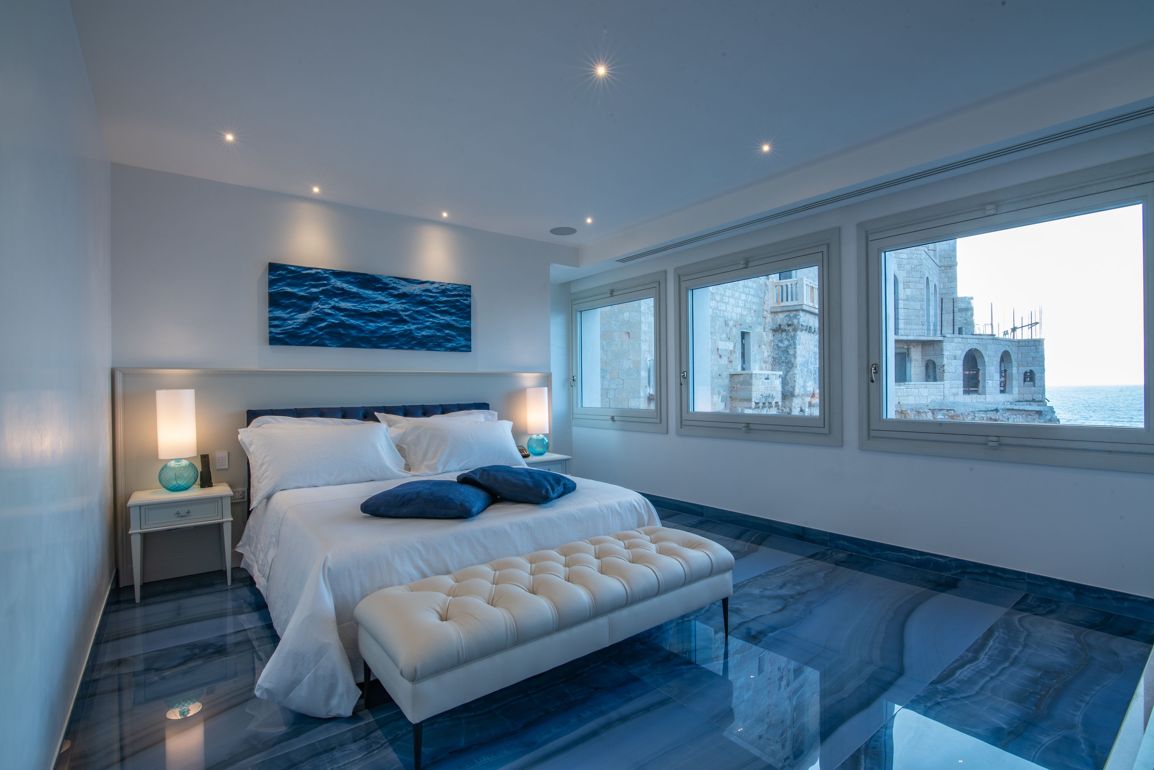 Una camera da letto moderna con un letto grande, una panca e vista su un edificio storico.