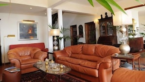 Ein geräumiges Wohnzimmer mit Ledersofas, einem Couchtisch und einem Kamin.