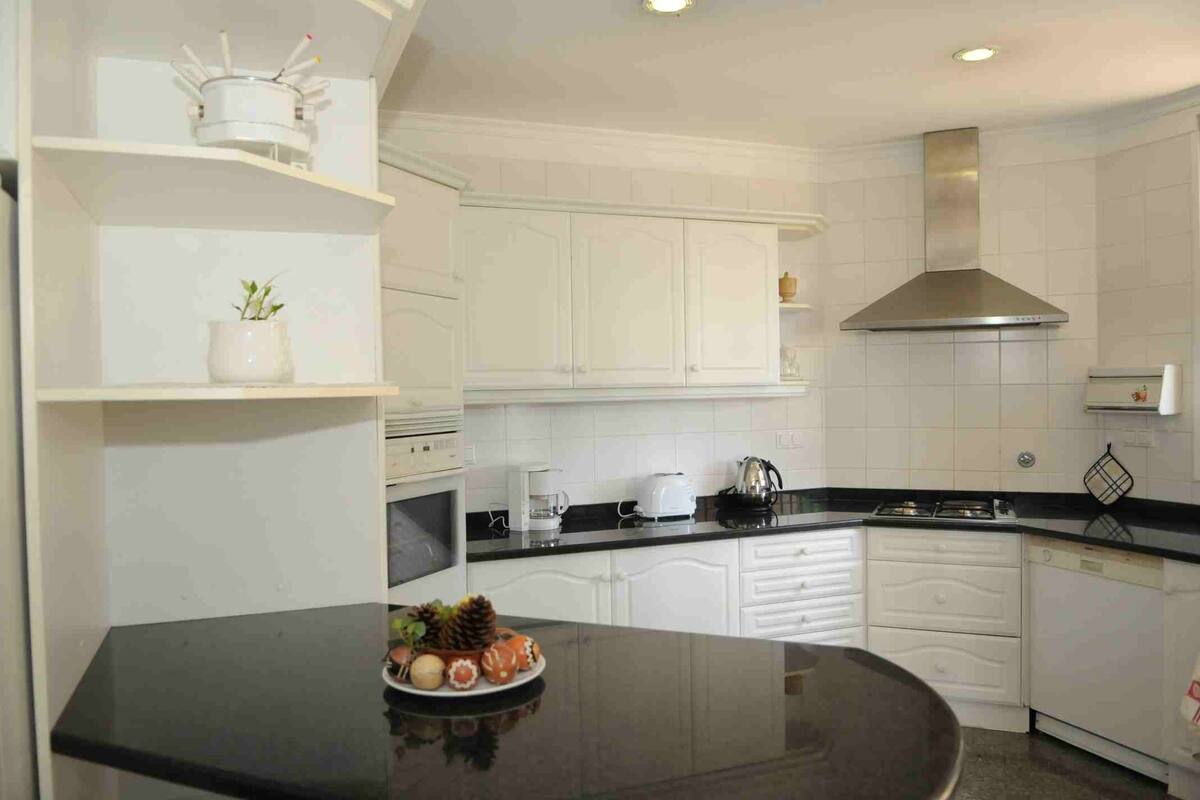 Een moderne keuken met witte kasten, een zwart aanrecht en een roestvrijstalen afzuigkap.