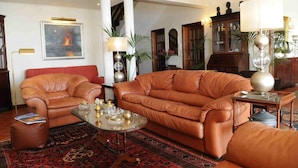 Ein geräumiges Wohnzimmer mit Ledersofas, einem Couchtisch mit Dekoration und einem großen Gemälde an der Wand.
