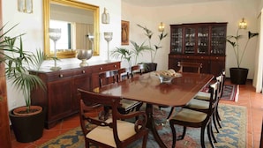 Ein Esszimmer mit einem großen Holztisch, Stühlen, einem Schrank und Topfpflanzen.