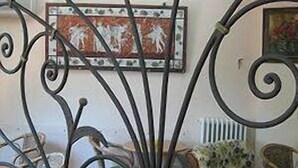 Una habitación con una reja metálica, un cuadro en la pared y un sofá estampado.