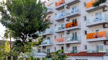Un hotel con varios balcones, una piscina con tumbonas y un flotador junto a la piscina.
