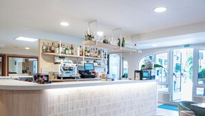 Un espace bar moderne doté d’un comptoir, de sièges et offrant une vue sur l’extérieur.