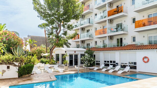 Une piscine avec des chaises longues et un bâtiment doté de balcons.