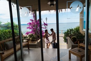A hotel entrance with a view of the sea, a wooden bench, and potted plants. - Hotel Miramare - Adults Only (Trieste)
