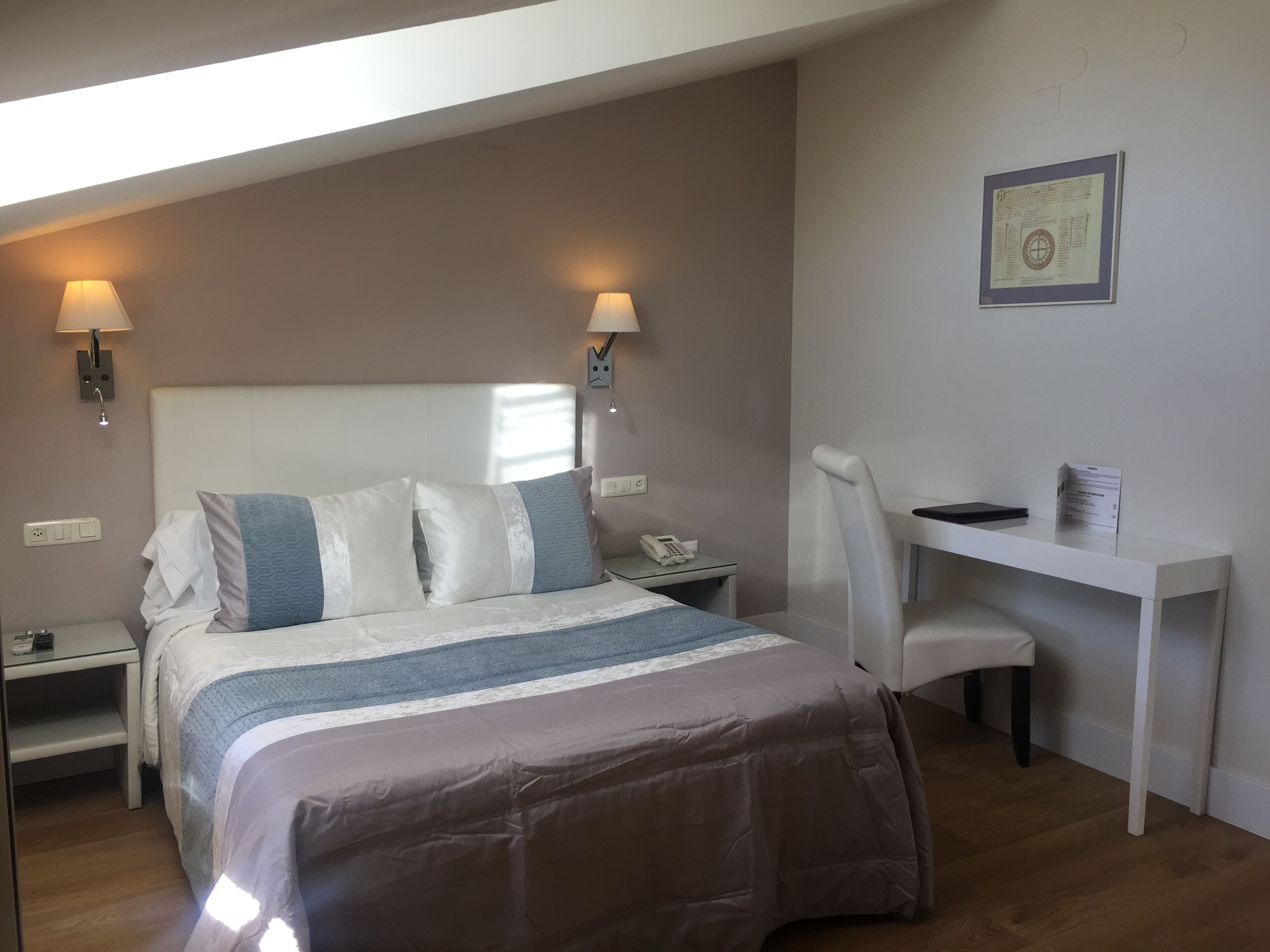 A bedroom with a bed, bedside tables, a desk, and a chair.