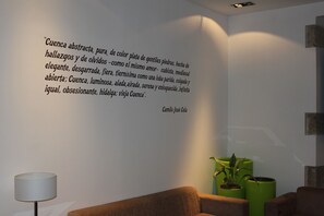 A modern interior with a quote on the wall, a lamp, and green planters. - Hotel Leonor de Aquitania (Cuenca)