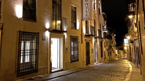 A cobblestone street lined with historic buildings, a hotel sign, and a pedestrian sign. - Hotel Leonor de Aquitania (Cuenca)