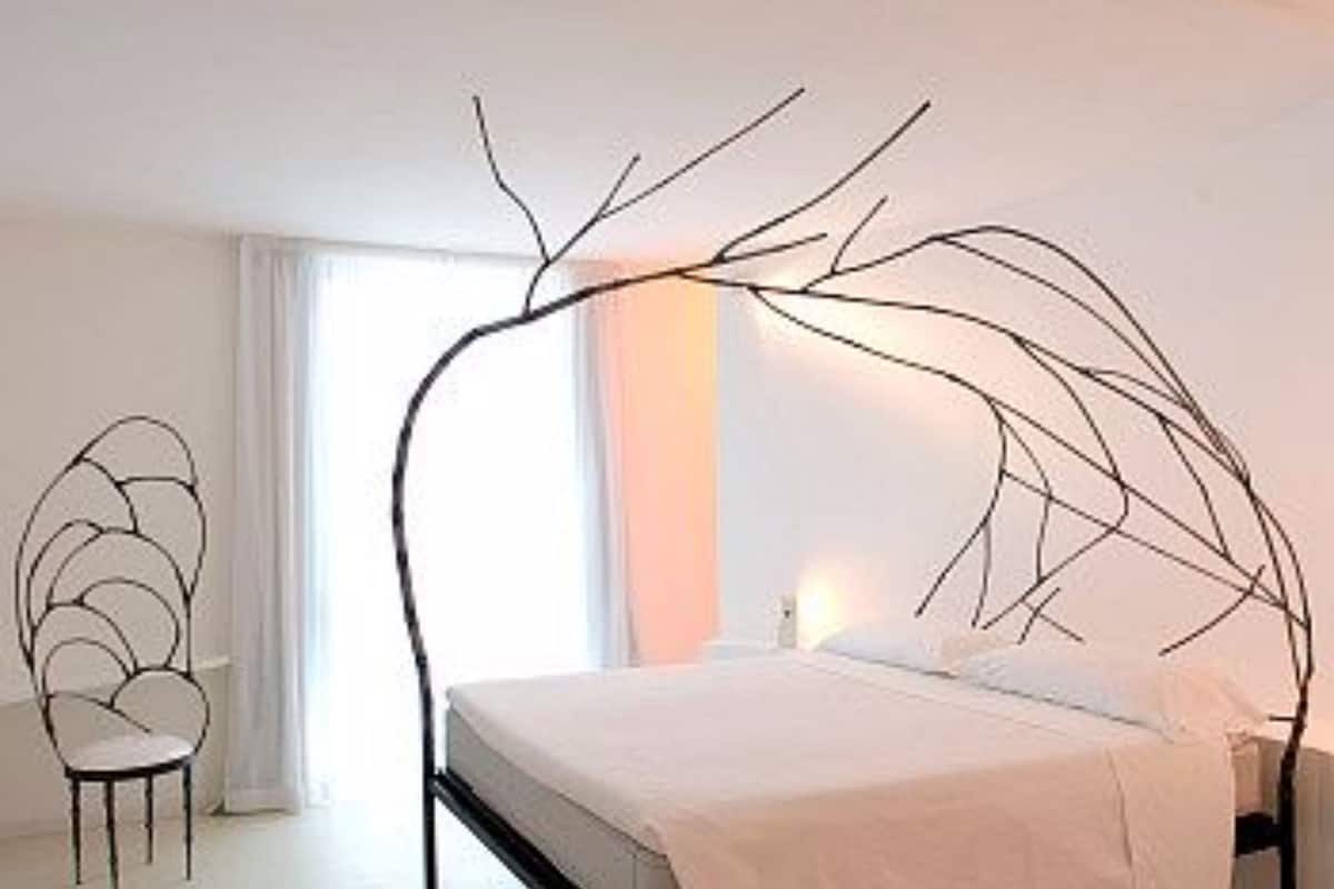 Ein schlicht eingerichtetes Schlafzimmer mit einem Bett, einem Sessel und einem großen Fenster.