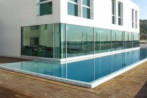 A modern building with a large glass facade and a swimming pool in front. - Alexander Museum Palace Hotel (Pesaro)