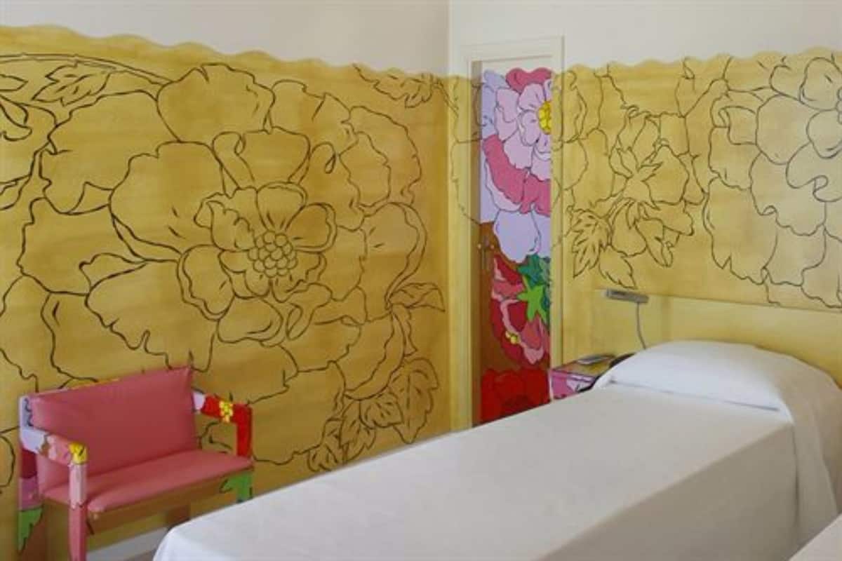 Ein Zimmer mit einem Bett, einem Sessel und einer Wand mit Blumenmuster.