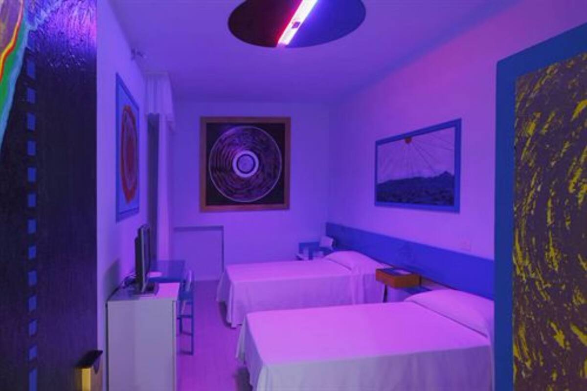 Ein Zimmer mit zwei Betten, einem Schreibtisch und einem runden Wandbild.